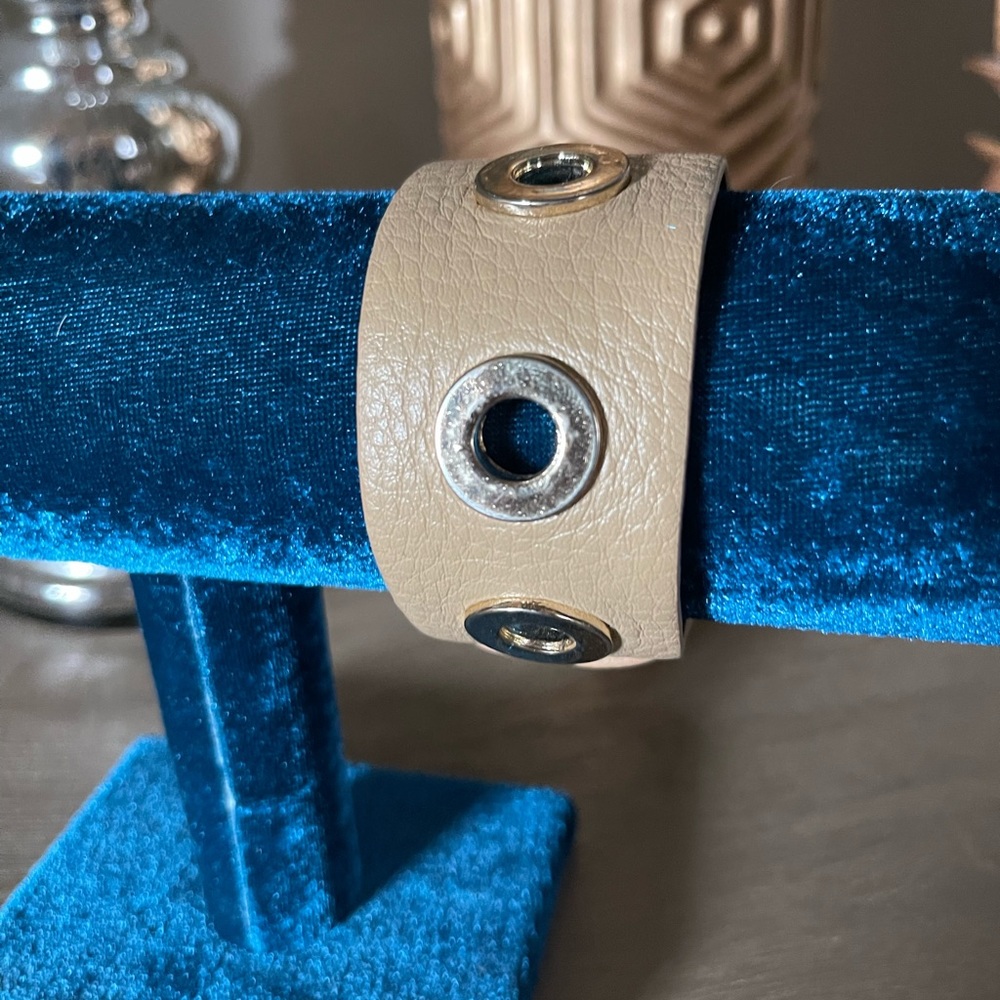 Faux leather cuff with gold eyelets.